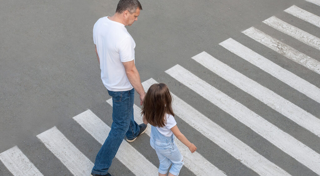 Child practicing street safety skills with parent support